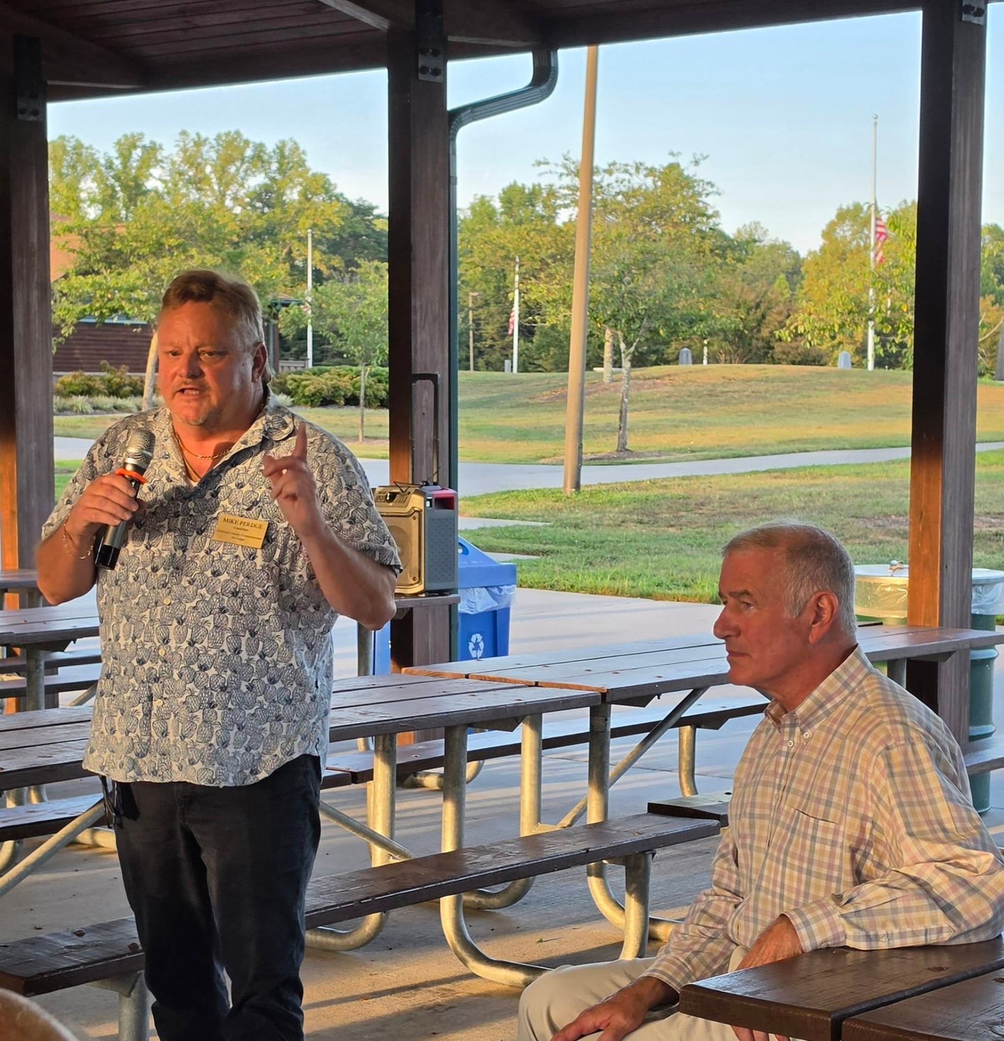 Mike Perdue speaking at an outdoor community gathering.
